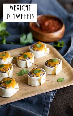 mexican pinwheels on a wooden platter with guacamole in the background