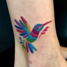 a colorful bird tattoo on the ankle