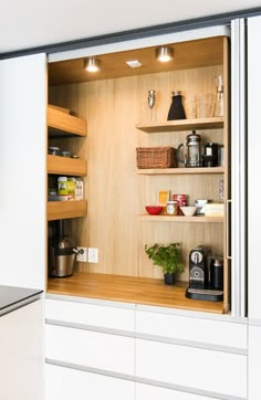 an open cabinet door in a kitchen with white cabinets and shelves filled with food items