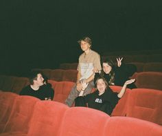 four people are sitting in the middle of an empty theater seat and one person is waving