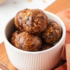 a white bowl filled with cookies on top of a wooden cutting board next to an orange towel