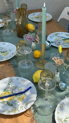 the table is set with plates, glasses and lemons on it for an elegant meal