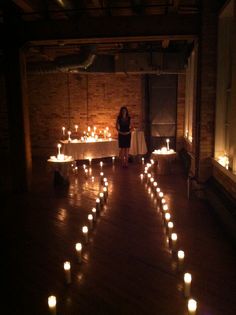 a woman standing in front of a table with candles on it and lights all over the floor