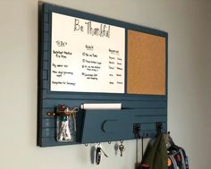 a bulletin board mounted to the side of a wall with magnets and hooks on it