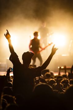 a man standing in front of a crowd at a concert with his arms raised up