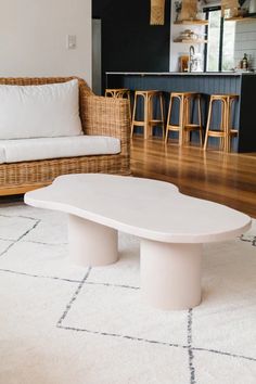 a white coffee table sitting on top of a wooden floor next to a couch and bar