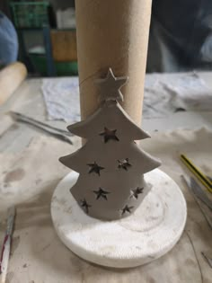 a small christmas tree made out of cardboard on top of a wooden table next to some scissors