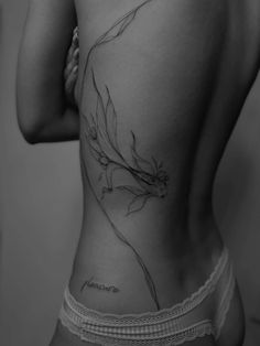 the back of a woman's stomach with a flower tattoo on her left side