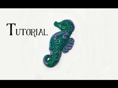 a green seahorse brooch sitting on top of a white table next to the words,