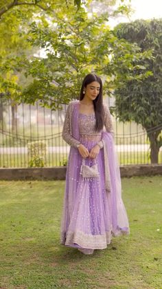 a woman in a purple dress standing on the grass