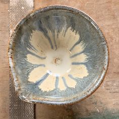 a white and blue bowl sitting on top of a wooden table next to a piece of cloth