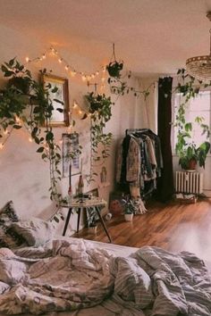 an unmade bed sitting in a bedroom next to a window with plants growing on it