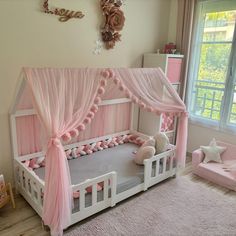 a child's bed with pink curtains and pillows