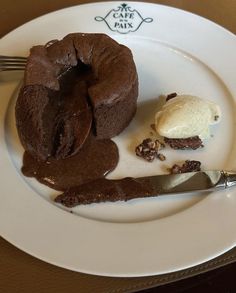 a chocolate cake and ice cream on a white plate with a silver fork next to it