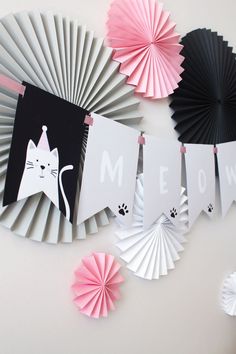 some paper fans are hanging on the wall and there is a cat banner that says meow