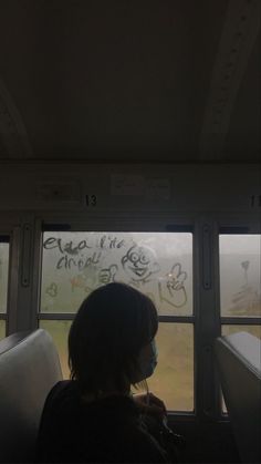 a person sitting on a bus looking out the window with graffiti all over it's walls