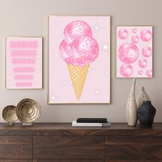 three pink ice cream posters hanging on the wall above a dresser with vases and other items