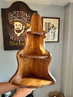 a wooden shelf hanging from the ceiling in front of a wall with pictures on it