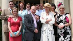 a group of people standing in front of a building with their arms crossed and looking at the camera