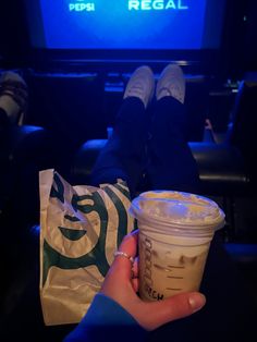 a person holding up a drink in front of a tv