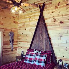 a bed in a room with wooden walls and ceiling fan on the wall above it