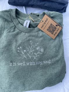 Floral "It is well with my soul" embroidered Christian t-shirt. ☆ DESCRIPTION  50 % Cotton   50% Polyester  Color: Heather Army Green, White Text Sizes Offered : S, M, L, XL  SHIPPING ☆ These shirts are handmade and made to order, making each purchase individually stitched with care. Due to this, I do require a 3-5 day processing time per each order.   For high quantity orders of 4+ items, please allow a 5-7 day processing time. If you have a deadline, please message me upon order and I will make it my priority to expedite the production process!   RETURN POLICY ☆ If you need to return/exchange this item for any reason, please let me know. If there is any defect in your product-- I will send you a new one!  ☆ WASHING/CARE INSTRUCTIONS ☆ Machine wash in cold water, dry on a low temperature Catholic Shirt, Jesus Clothes, Christian Shirts Designs, Mama Cloth, It Is Well With My Soul, Mama Style, Christian T Shirt, Christian Shirt, Little Outfits