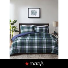 a plaid comforter set with blue and white sheets on a bed in a bedroom