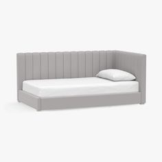 a bed with a white pillow on it and a gray headboard that is attached to the wall