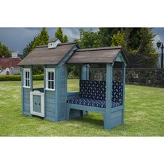 a small blue and white wooden house with a couch in the yard next to it