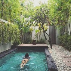 a person swimming in a pool surrounded by trees