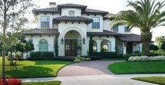 a large white house with palm trees in the front yard and landscaping on both sides