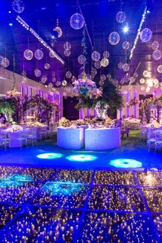 a room filled with lots of tables and chairs covered in blue lights, surrounded by disco balls