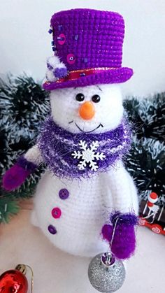 a crocheted snowman with a purple hat and scarf