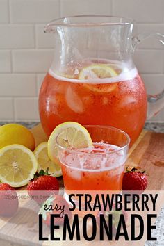 a pitcher of strawberry lemonade next to some strawberries and lemons on a cutting board