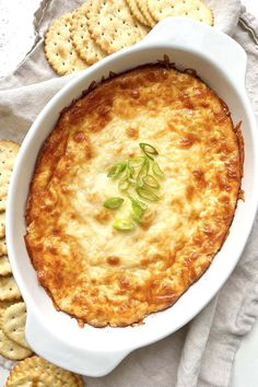 a casserole dish with cheese and crackers on the side, ready to be eaten