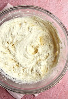 a glass bowl filled with white batter on top of a pink tablecloth and napkin