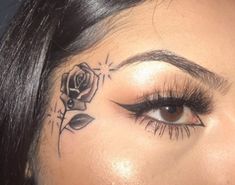 a close up of a woman's face with a rose tattoo on her forehead