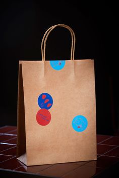 a brown paper bag with blue and red circles on the side sitting on a table