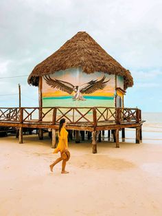 a woman running on the beach in front of a hut with an eagle painted on it