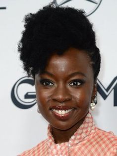 a close up of a person with an afro haircut and wearing a checkered shirt