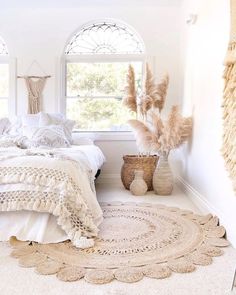 a white bedroom with an oval rug and round windows