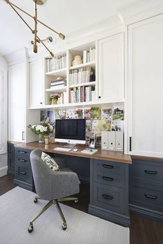 a home office with white cabinets and gray desk