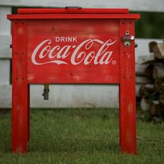 an old coca - cola sign sitting in the grass