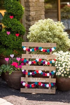 a wooden sign that says welcome to our wedding next to potted plants and flowers