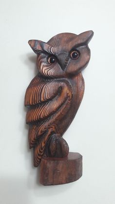 an owl statue is sitting on top of a piece of wood