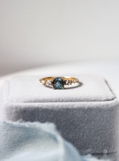 an engagement ring with two diamonds in it sitting on top of a white cloth box