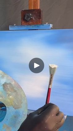 a person holding a paintbrush in front of an easel