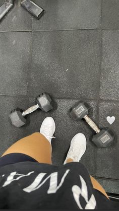 a person standing next to two dumbbells on the ground with their feet up