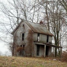 an old run down house in the middle of some trees with no leaves on it