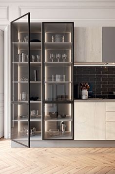 an open glass cabinet in the middle of a kitchen with wooden floors and white walls